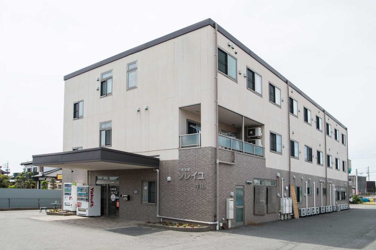 介護施設の建物外観。3階建てで白壁とレンガ造りの現代的な施設。