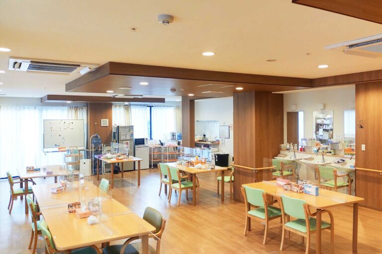 木調の温かみある食堂。複数のテーブルが配置され、明るく清潔な空間。